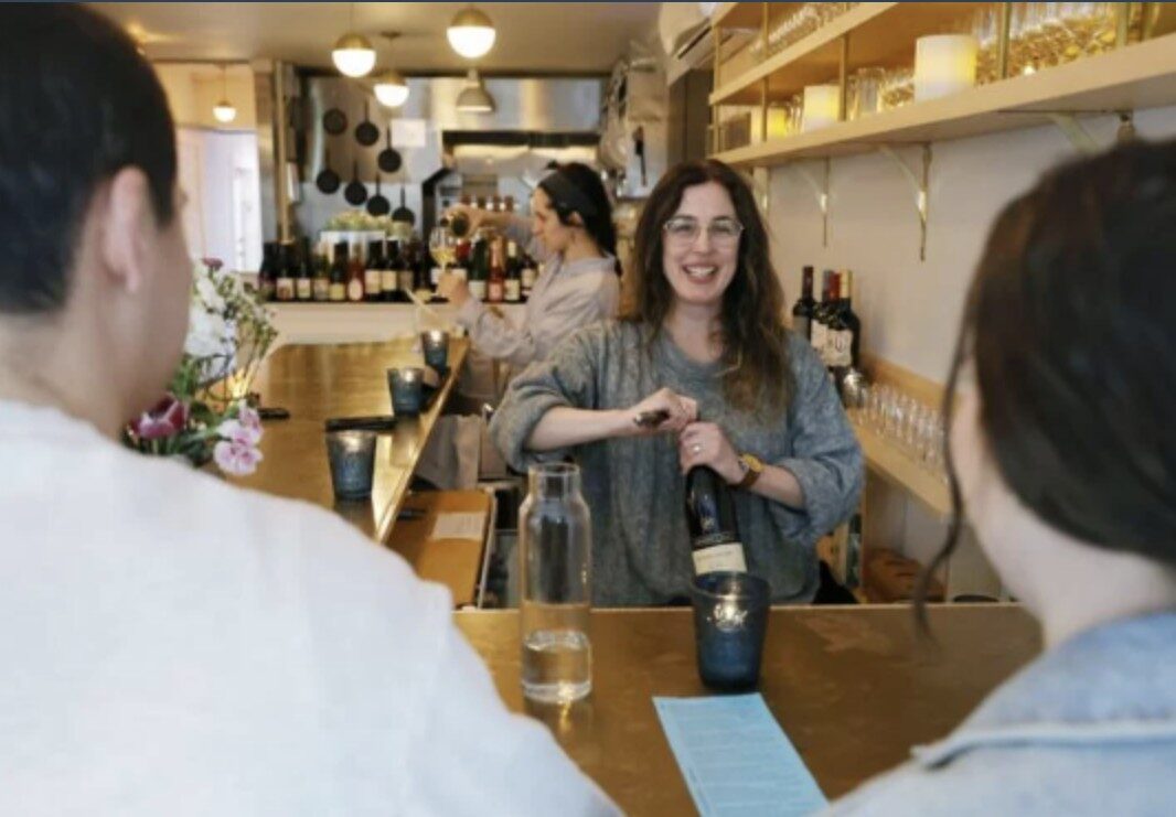 Bartender opens bottle of wine for guests.